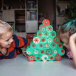 Dívka a chlapec si společně prohlížejí ručně vyrobený adventní kalendář ve tvaru stromku