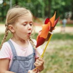 Děvče foukající do větrníku