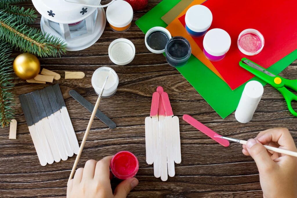 Malování slepených dřívek červenou a černou barvou na Santu a sněhuláka.