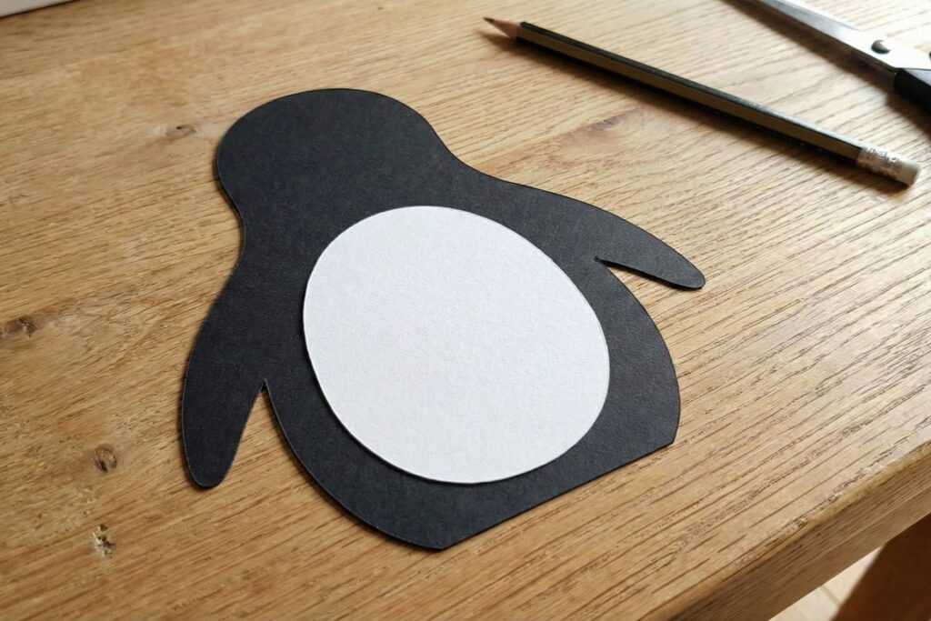 Bílý papírový ovál jako podklad pro vatu na břiše tučňáka.