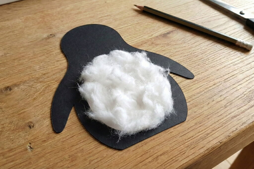 Detail nalepování bílé vaty na papírový podklad.