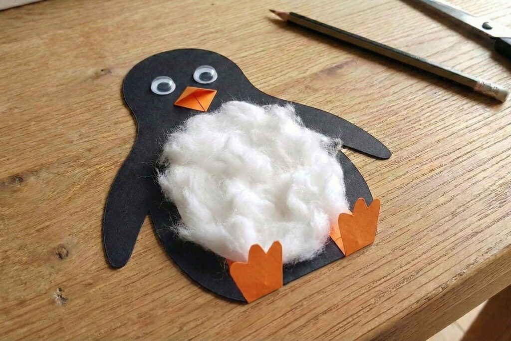 Oranžové papírové tlapky tučňáka ohnuté pro stabilitu.