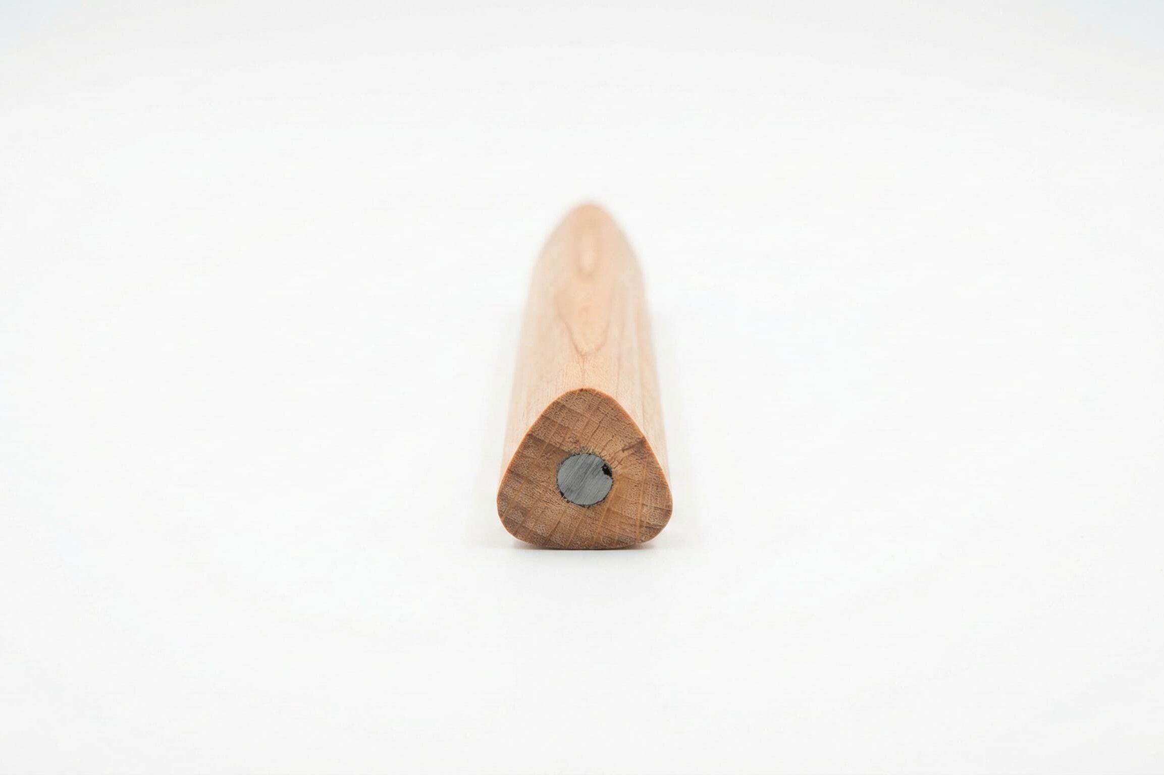 Silná trojhranná dřevěná tužka pro nácvik správného úchopu na bílém pozadí.